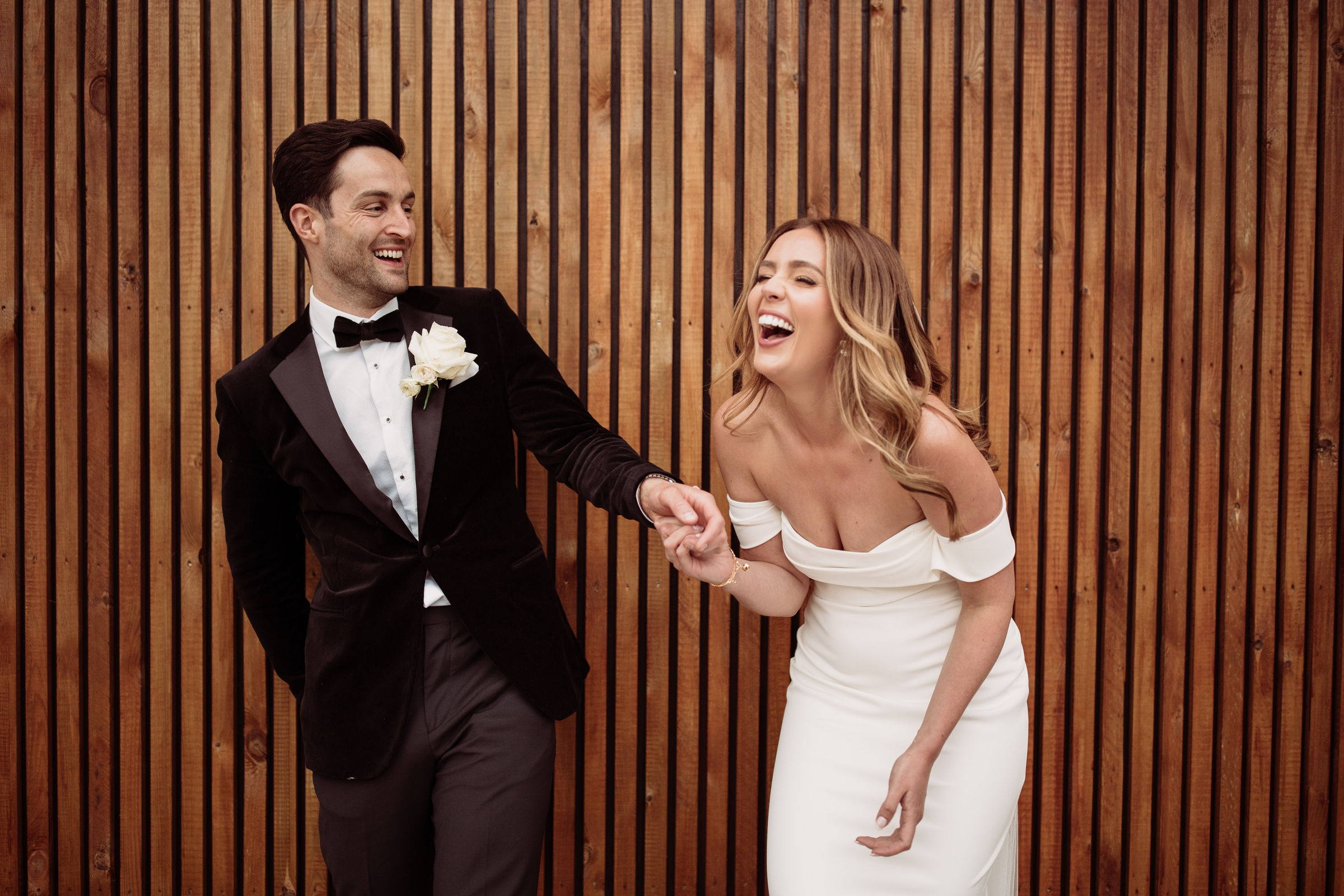 A couple laughing together against dark timber