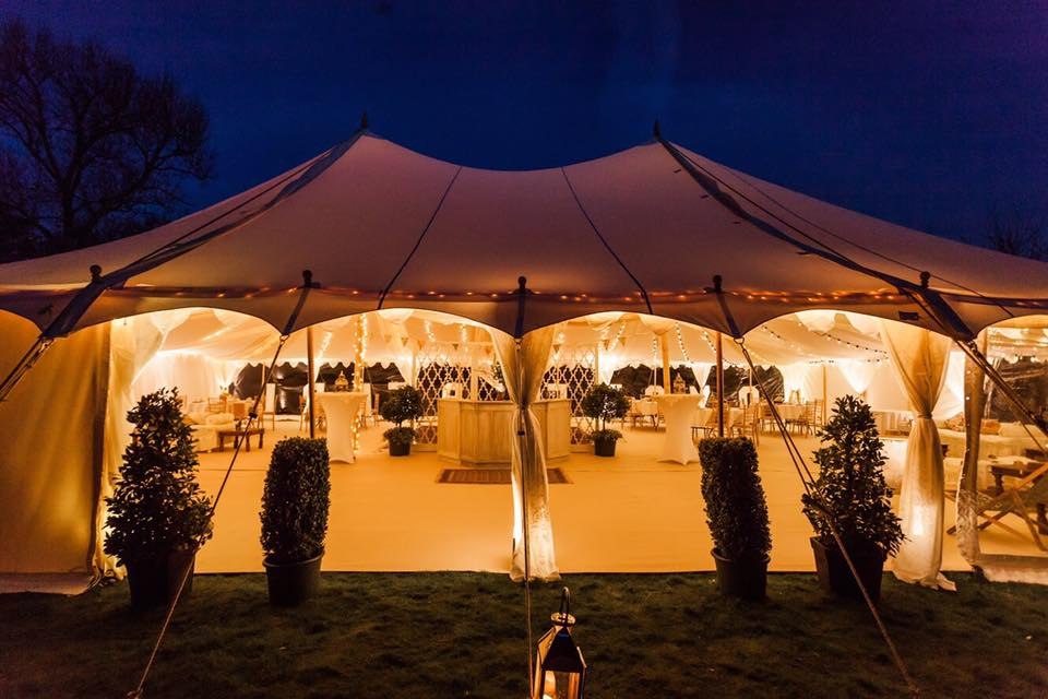 Guests inside an illuminated reception tent at Goodnestone Park