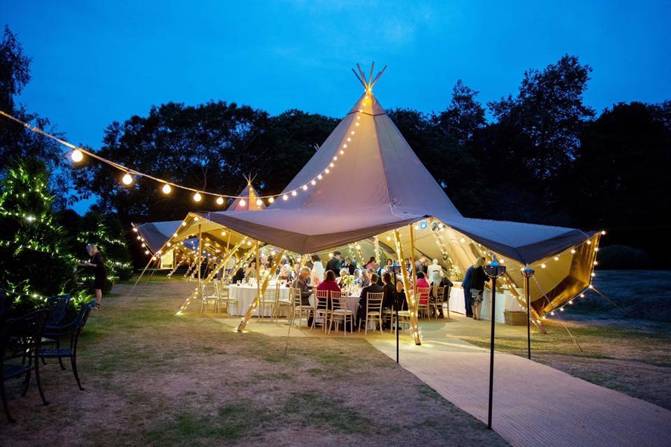An illuminated marquee in the gardens at Goodnestone Park