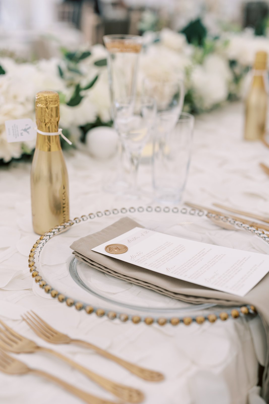 A wedding menu and gold cutlery at a marquee table