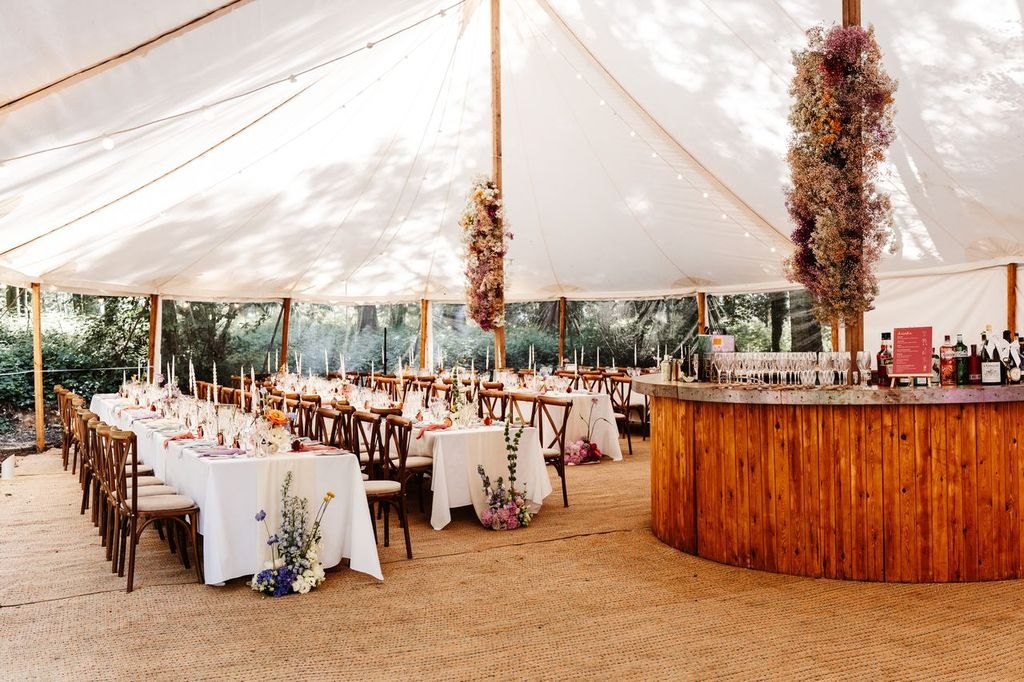 A marquee set for a celebration with dining tables and a bar