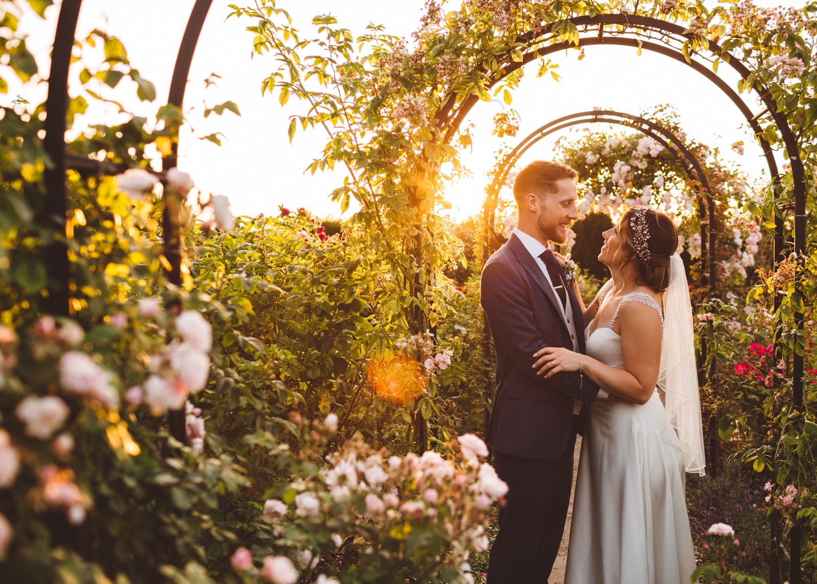 A couple beneath a garden arch in the evening sunlight at Mount Ephraim