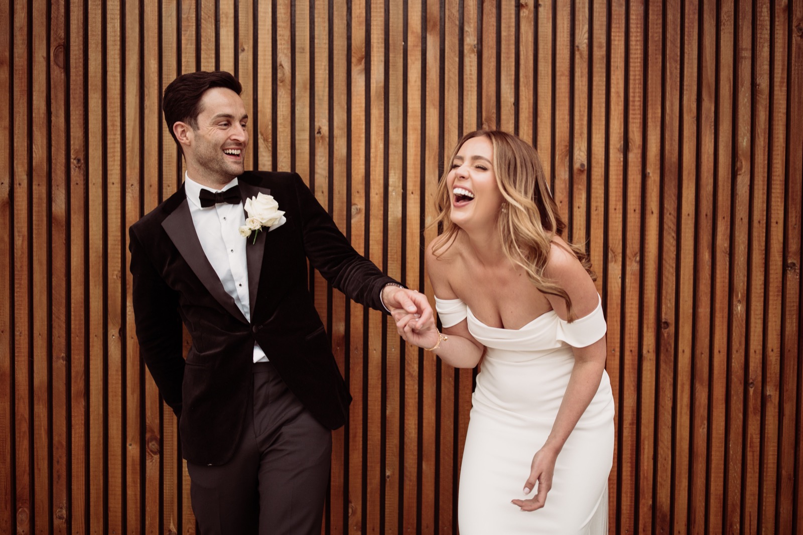 A couple laughing beside the timber wall at Oad Street