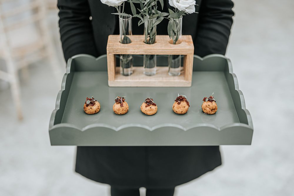 Canapés carried through the garden on a dove-grey tray