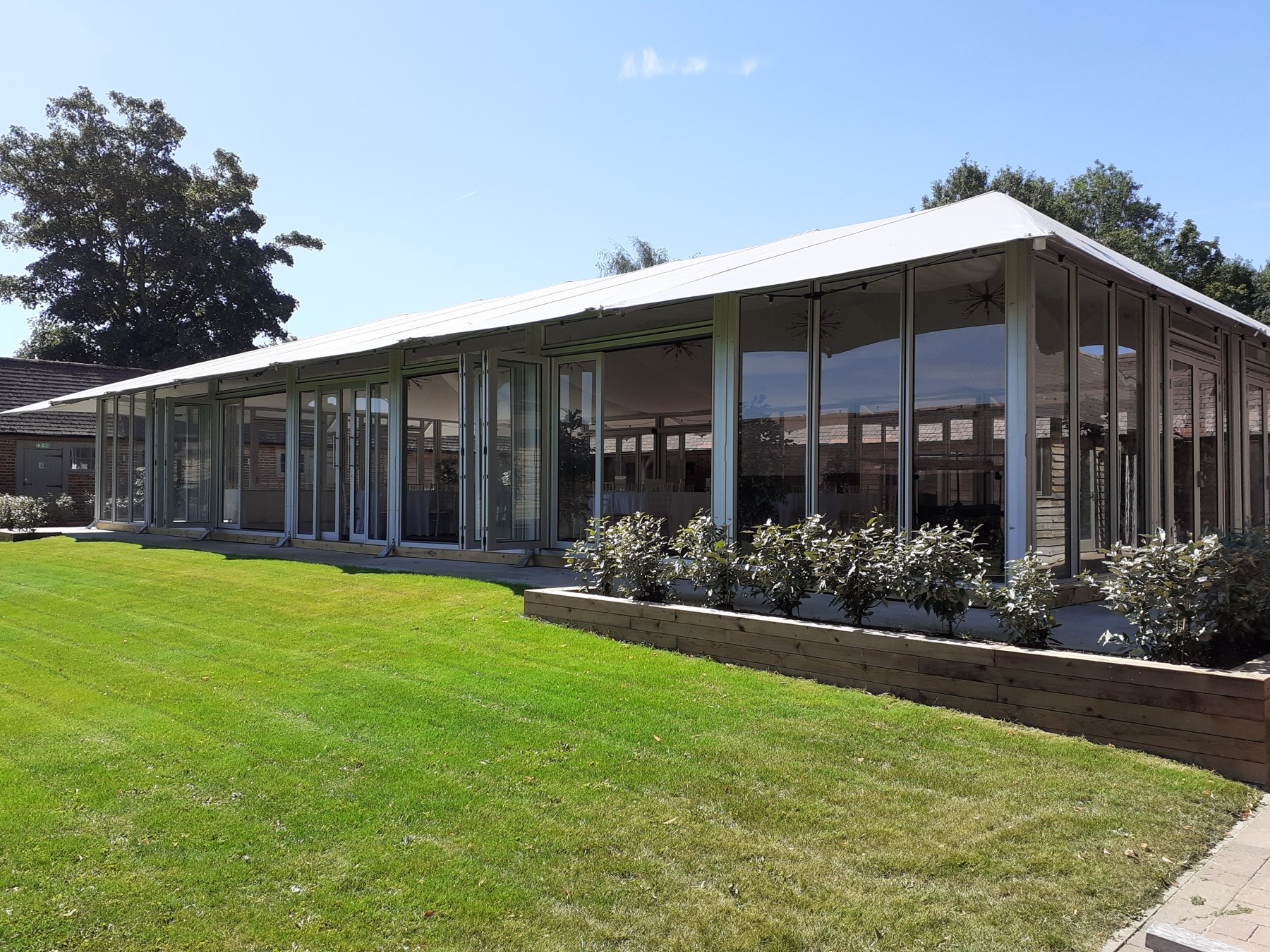 The glazed reception space beside the courtyard lawn at The Night Yard
