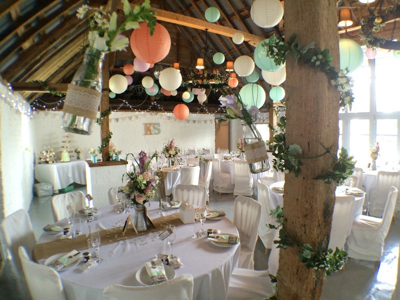Reception tables and colourful hanging lanterns at The Red Barn