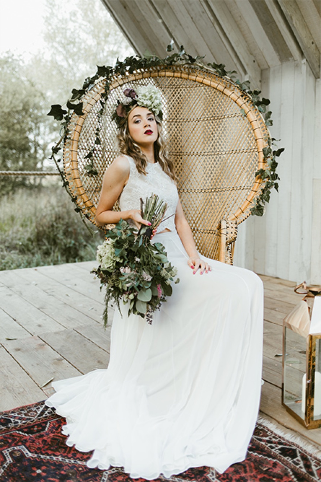 A bride seated in a wicker chair with her bouquet