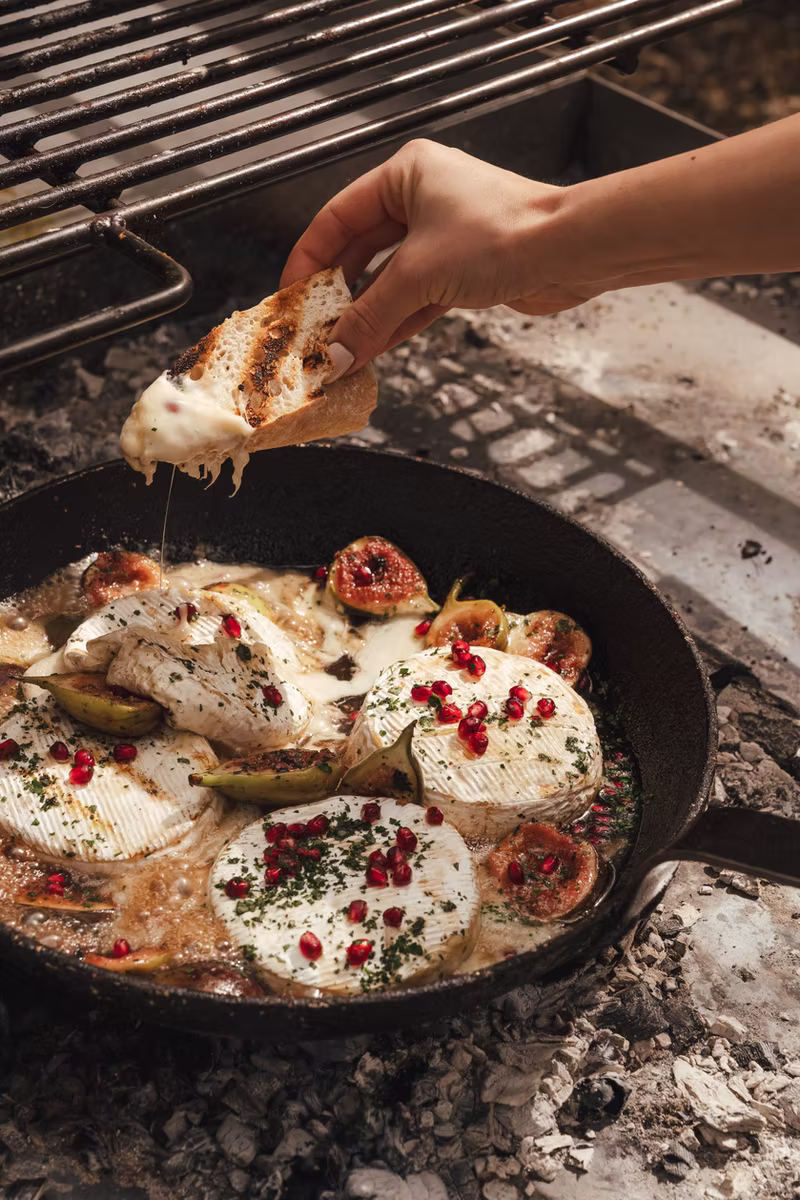 Warm camembert topped with colourful garnishes, served beside the grill