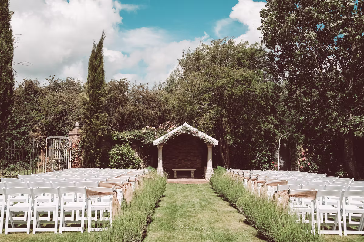 White chairs and a timber shelter set for a garden ceremony at Marleybrook House