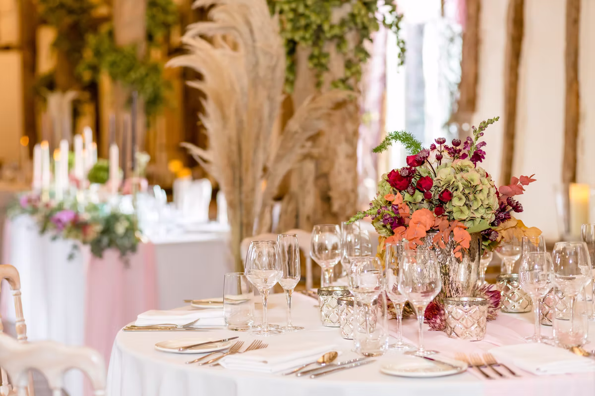 Flowers, candles and place settings on a wedding table at Winters Barns