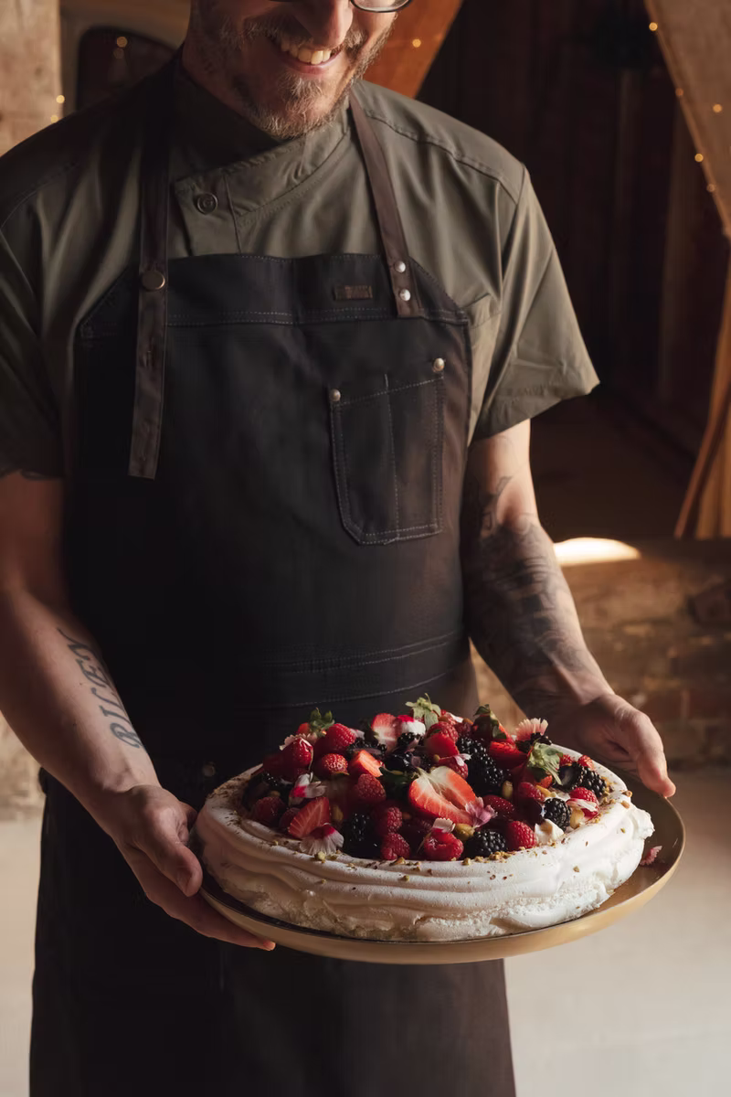 A chef holding a generous berry pavlova