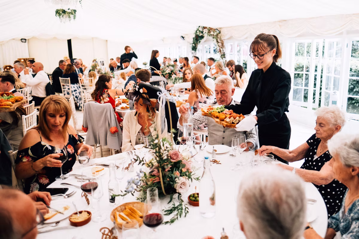 A member of the waiting team serving guests at a wedding breakfast