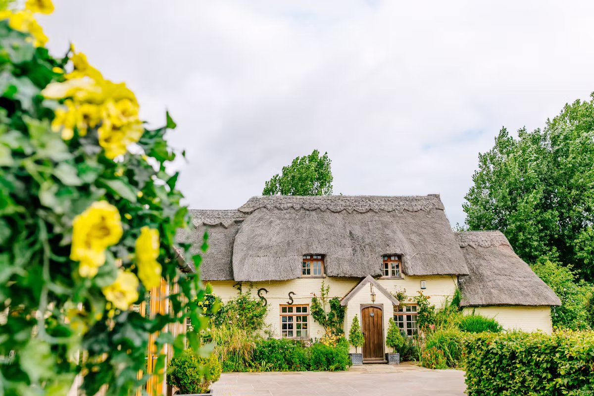 The thatched farmhouse viewed through the gardens at Marleybrook House