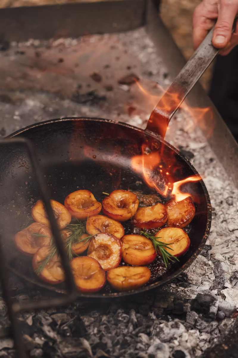 Peaches caramelising in a pan over the fire